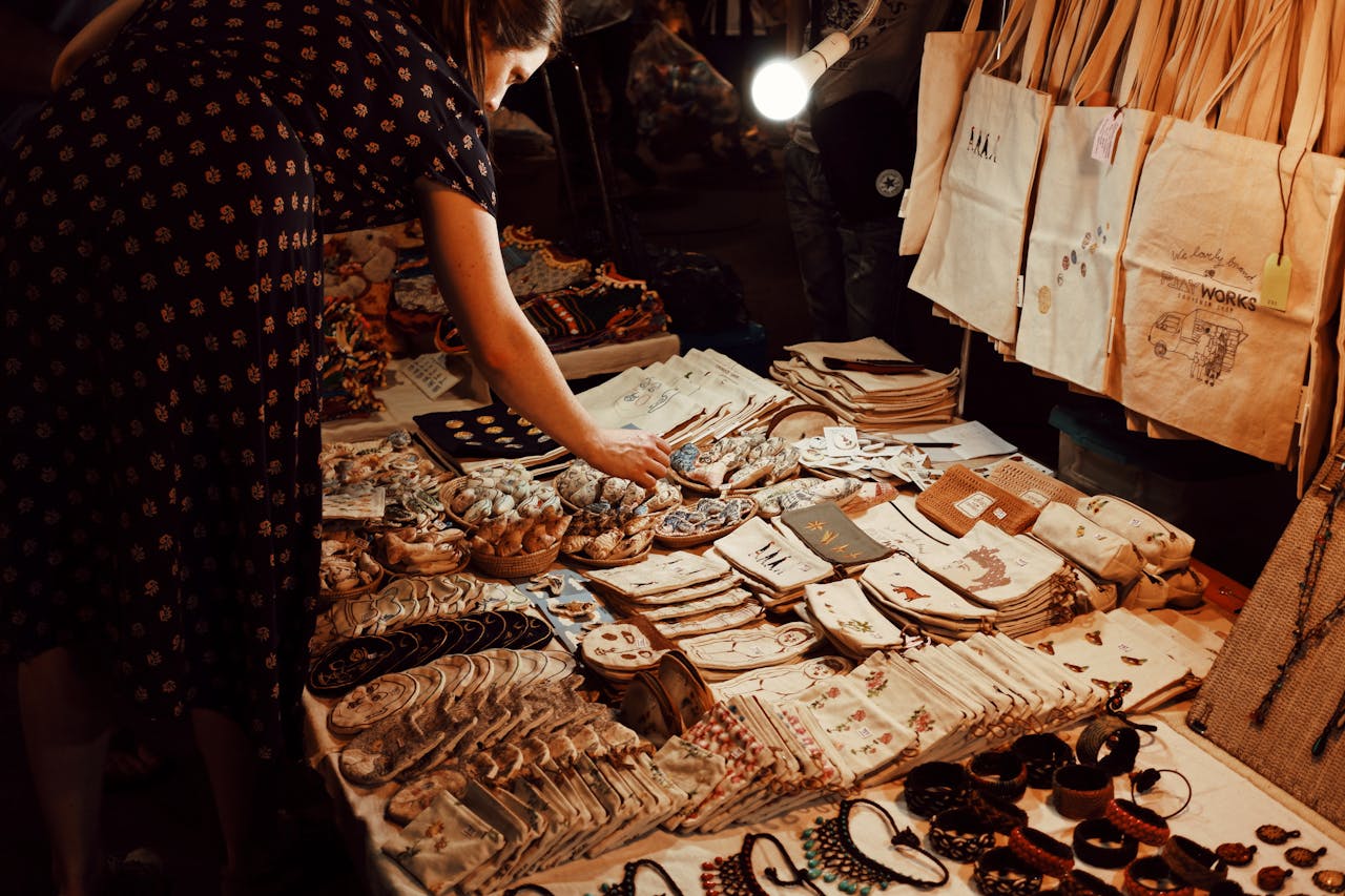A woman browsing handmade crafts at a vibrant local market stall.